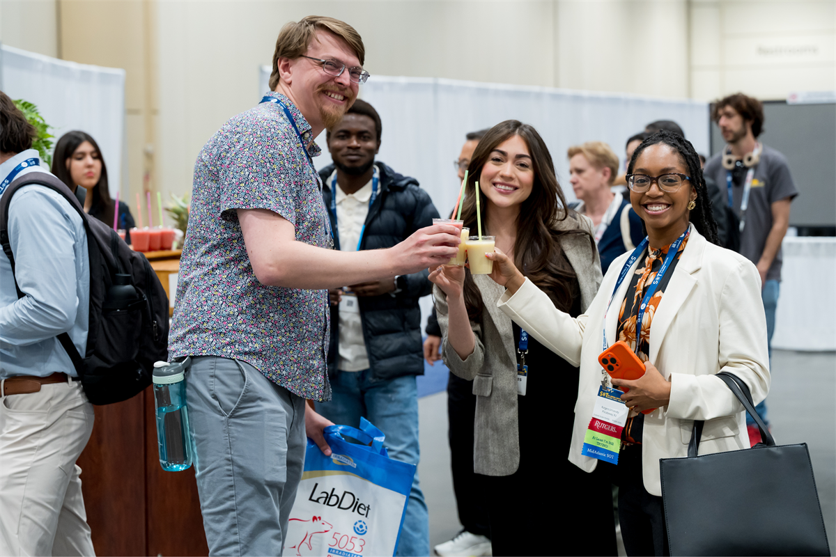 Three people smiling at the camera clinking coffee cups.